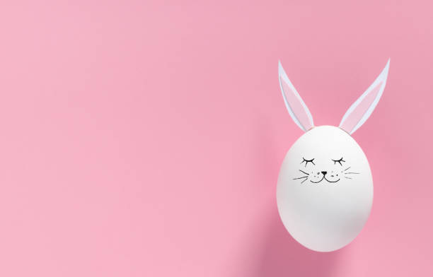 istock Easter egg with bunny ears and face on pink background with copy space. Flat lay or top view. Minimal concept. Conceptual creative photo approaching Happy Easter holiday 1297493813