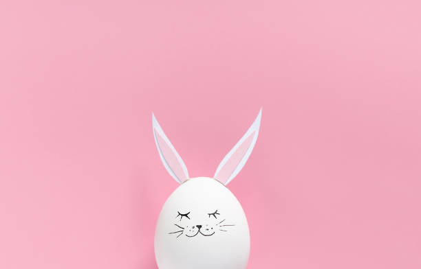 istock Easter egg with bunny ears and face on pink background with copy space. Flat lay or top view. Minimal concept. Conceptual creative photo approaching Happy Easter holiday. 1297493815