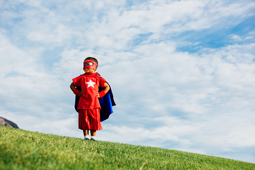 A young boy dressed as a superhero with mask and cape shows his courage and strength in life, but facing his fears and conquering them.