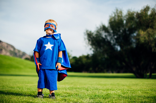 A young boy dressed as a superhero with mask and cape shows his courage and strength in life, but facing his fears and conquering them.