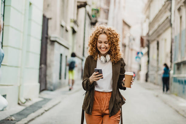 istock Young woman is using mobile phone on the move and holing reusable coffee cup 1297495941
