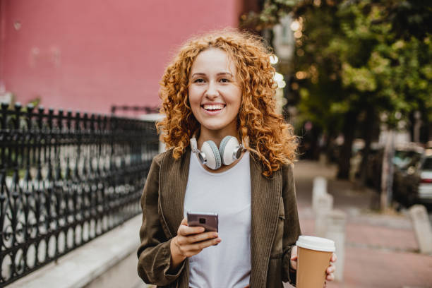istock Young woman is using mobile phone on the move and holing reusable coffee cup 1297496160