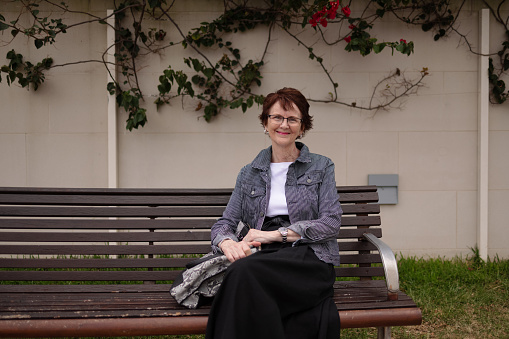 Woman sitting on a bench in front of a wall.