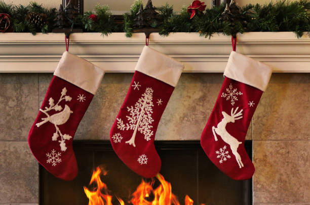 gemütlicher weihnachtskamin mit drei roten strümpfen - strumpfwaren stock-fotos und bilder