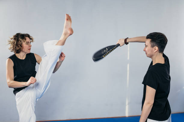 addestramento personale arte marziale del taekwondo. allenatrice donna che tiene il kick pad taekwondo, gli allenatori atleti calci. donna che calcia scudo d'attacco, allenamento sparring con l'allenatore. combattenti che si allenano insieme - karate women kickboxing human foot foto e immagini stock