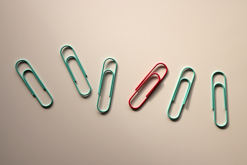 Blue and pink paper clips over white background.