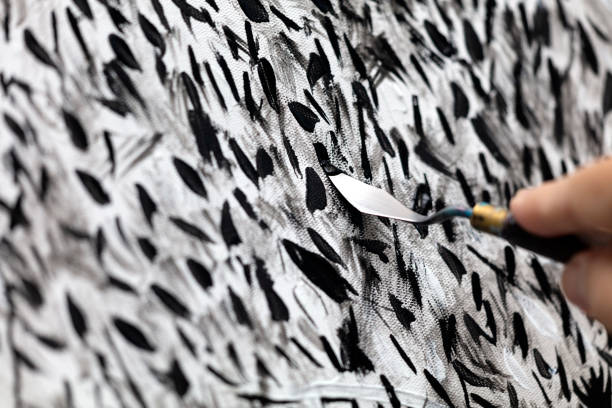Close up of artist hand painting on canvas with spatula.
