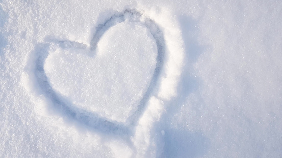 heart drawn on the snow in the park. Valentine's Day, winter vacation in the city.