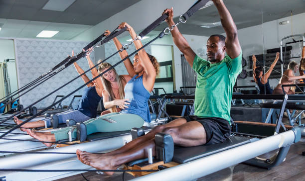 tre adulti nello studio di pilates con istruttore di fitness - pilates machine foto e immagini stock