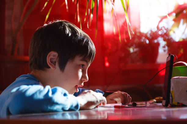 istock home online training, a boy using a mobile phone and headphones is engaged in English speaking 1297510554