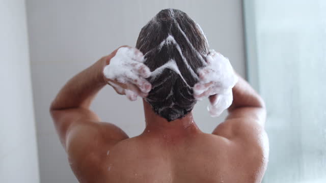 Man taking a shower washing hair with shampoo product under water f