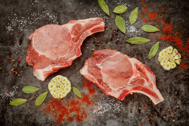 onkookte varkensvleeskarbonades rib met kruiden op grijze achtergrond. - karbonade stockfoto's en -beelden