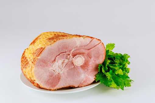 Whole pork ham with fresh celery isolated on white background. Easter dish.