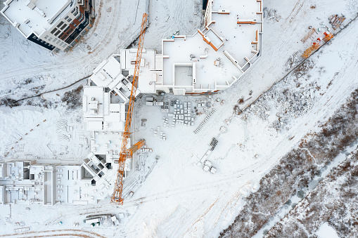 Top view of a construction site with cranes covered with snow. Aerial cityscape.
