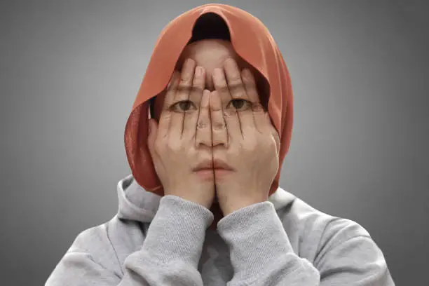 Photo of Mysterious Asian muslim covering her face with hands, multiple exposure shows her sad depressed face