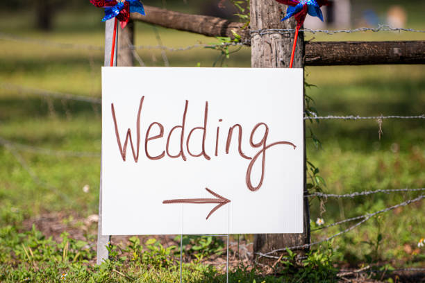 White directional wedding sign on grass that  reads \