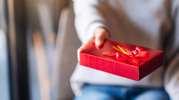 istock a woman holding and giving a red present box 1297528076