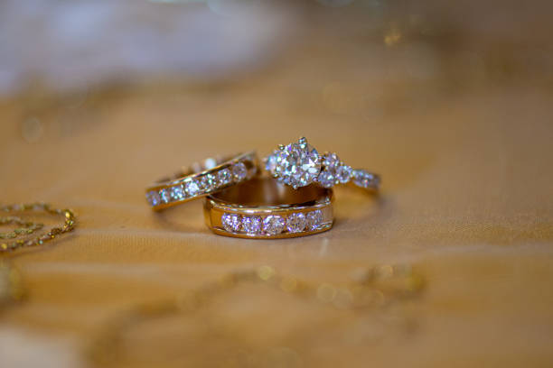 istock Gold bride and groom wedding rings with round diamonds on beige table cloth 1297529751