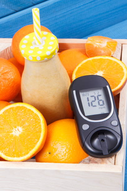 Glucometer with sugar level and smoothie from citrus fruits as source vitamins and minerals stock photo