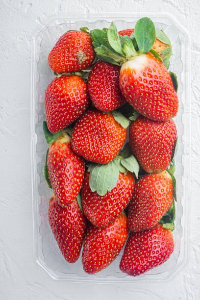 istock Transparent plastic tray with freshly picked strawberries, on white background, top view flat lay 1297533931