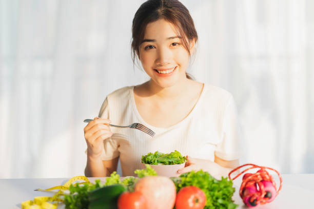 Woman home Young woman is eating green vegetables for weight loss WOMAN LOSING WEIGGHT stock pictures, royalty-free photos & images