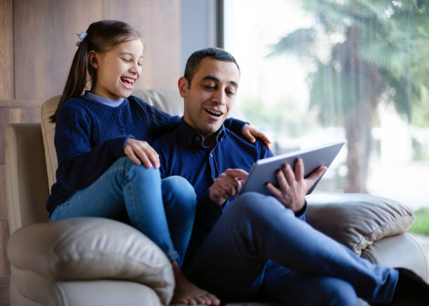 istock Father And Child Daughter At Home Watching On Digital Tablet And Having Fun 1297540190