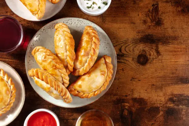 Empanadas dinner, shot from above on a dark rustic wooden background with a place for text