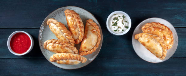 istock Empanadas with sauces, overhead flat lay panorama 1297540453