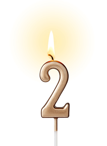 Burning birthday candle in the form of number two for cake isolated on white background.