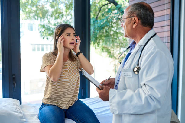 I have a headache that won't go away Shot of a mature doctor having a consultation with a young woman symptom photos stock pictures, royalty-free photos & images