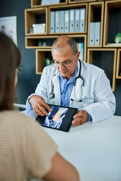 This is the site of your inflammation Shot of a doctor using a digital tablet during a consultation with his patient examining x ray stock pictures, royalty-free photos & images
