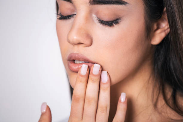istock Young woman touches her Mouth - Concept showing avoid touch face to protect and prevent form covid-19, sars cov 2 or coronavirus outbreak or spreading. 1297544921