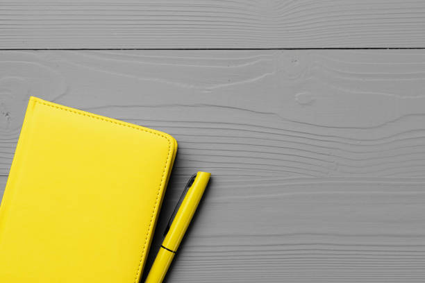 istock Yellow notepad on gray wooden background top view 1297547296