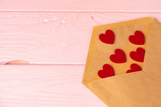 istock Red heart decoration in envelope on pink wooden table 1297547974