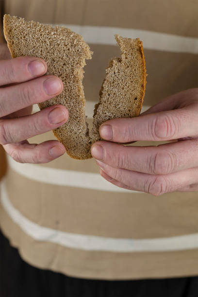 istock A man's hand splits a slice of rye bread in two. 1297549077