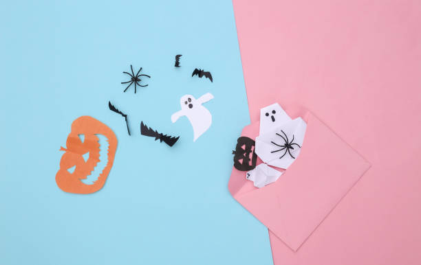 istock Envelope with handmade Halloween paper decor on pink blue pastel background. Halloween background. Top view 1297551627