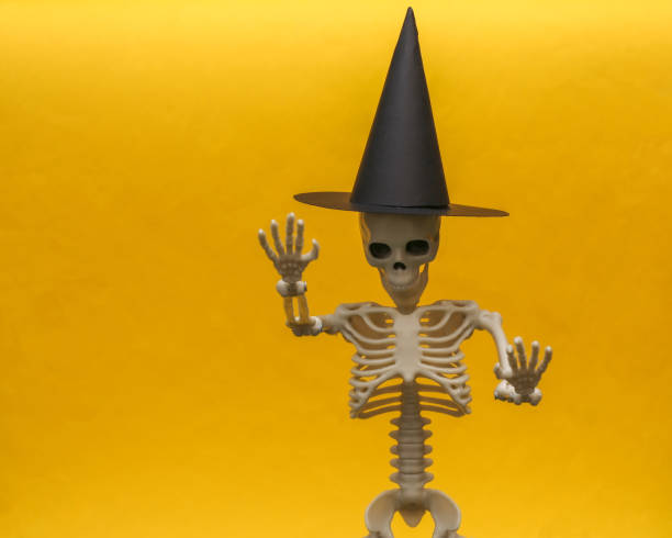 istock Skeleton in a witch's hat on a yellow background. Scary and Halloween theme 1297552182