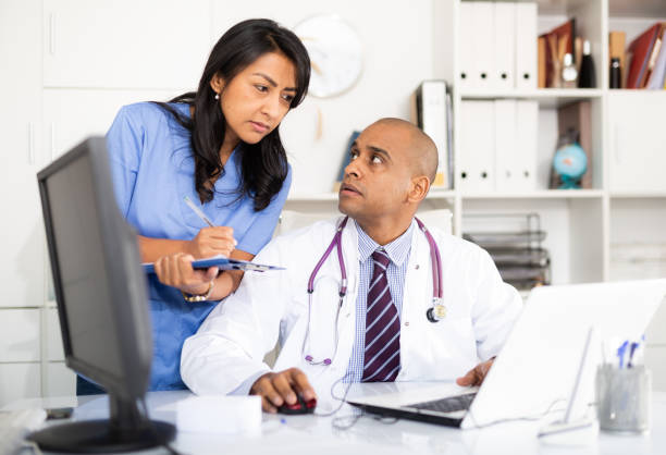 istock Two focused doctors working wit laptop in medical office 1297553615