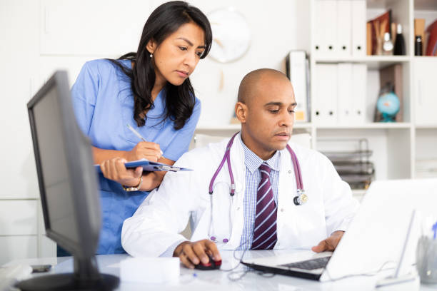 istock Two focused doctors working wit laptop in medical office 1297553623
