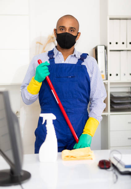 istock Male cleaner in protective mask and uniform at office 1297554703