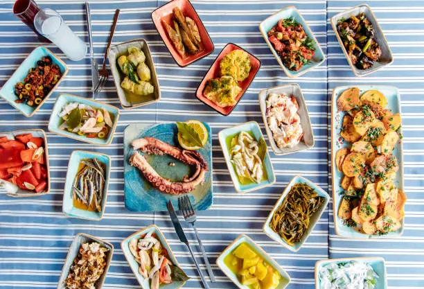 Seafoods, grilled meat, meze, herbs, fish, raki, ouzo, appetizers and salads in Greek or Turkish Fish Restaurant on the table for dinner or lunch at the beach from Greece or Turkey.