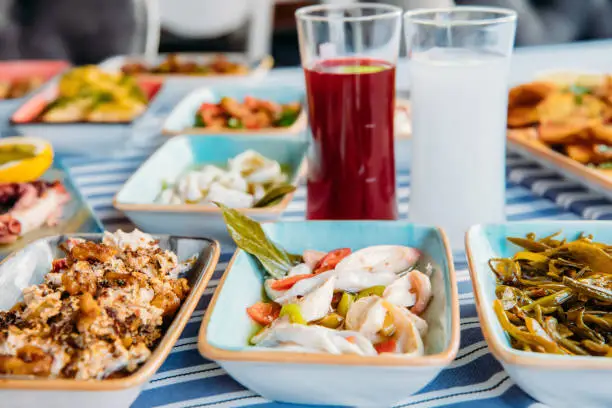 Seafoods, grilled meat, meze, herbs, fish, raki, ouzo, appetizers and salads in Greek or Turkish Fish Restaurant on the table for dinner or lunch at the beach from Greece or Turkey.