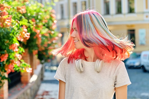 Hairstyles, hairs, fashion, trends, coloring. Close-up of fluttering colored dyed hair of young woman on sunny city street