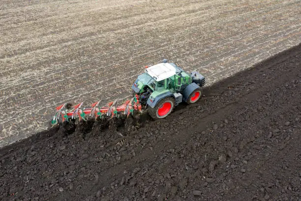Aerial view of an agricultural tractor plowing field.