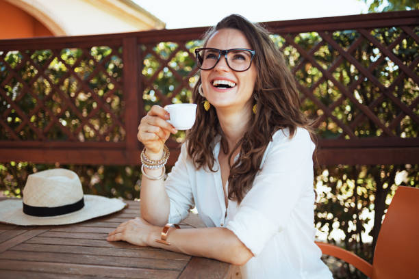 happy stylish woman in shirt sitting at table drinking coffee - summer people tourist slim imagens e fotografias de stock