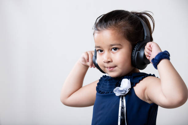 asian little girl listing music on wire less headphone with hands on ear. - toddler music asian ethnicity child imagens e fotografias de stock