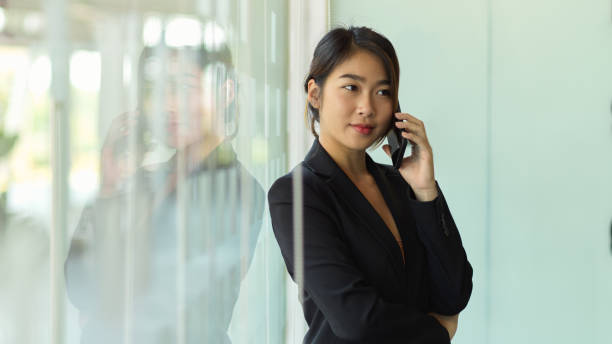 istock Businesswoman talking on the phone while standing in office room 1297564209