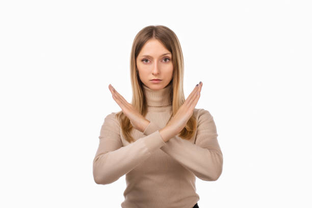istock Serious Young blond woman keeps two arms crossed, makes stop or ban gesture. Studio shot, white background 1297565466