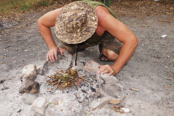 istock a man in a hat fanning a bonfire in nature 1297566809