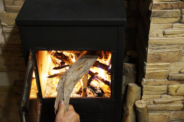 istock a man's hand puts firewood in a burning fireplace 1297566894